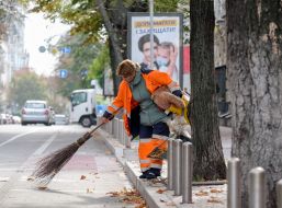 Сотрудница коммунальной службы убирает мусор