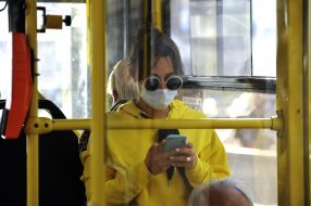 Girl in a medical mask and sunglasses in a trolleybus