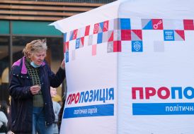 An elderly woman smokes near a campaign tent