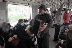 An elderly man plays the accordion in a subway car