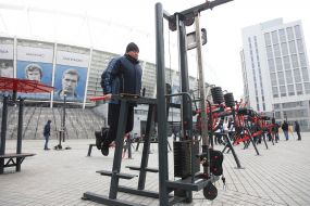 The man trains on the street exercise machine in the territory of the Open sports space of NSC "Olympic"
