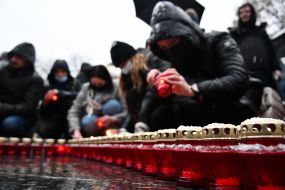 People lay out candles in the shape of a cross