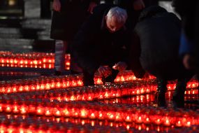 People lay out candles in the shape of a cross