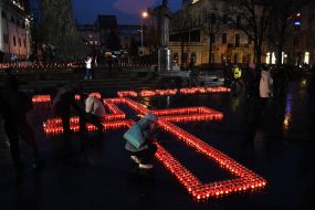 People lay out candles in the shape of a cross