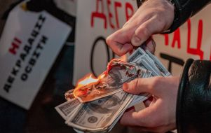 Мужчина поджигает символические бумажные деньги