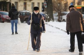 Женщина в медицинской маске с палкой идет по улице