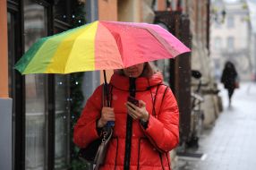 A woman with an umbrella walks down the street