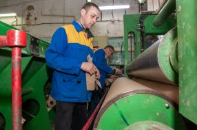 Рабочие готовят к резке рулон бумаги в сушильном цехе на Змиевской бумажной фабрике