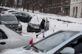Cars and a passerby on a snowy street