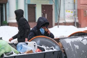A man rummages in a dumpster