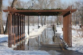 Женщина идет по затопленной водой дорожке в парке в Киеве