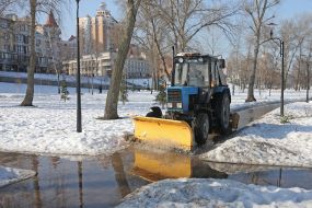 Трактор сгребает воду с затопленной дорожки в парке в Киеве