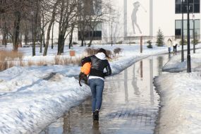 Женщина с собакой на затопленной водой дорожке в парке в Киеве