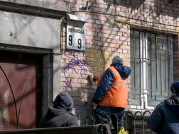 A utility worker paints over the painted facade of a residential building