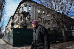 An elderly woman walks down the street in Mariupol