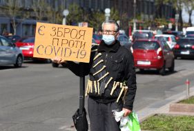 Чоловік тримає плакат з написом "Є зброя проти СОVID-19"