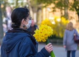 Woman in a medical mask with a bouquet of daffodils