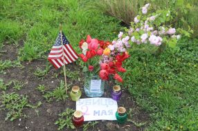 US flag near lamps, flowers and a poster with the words "May 2 killers"