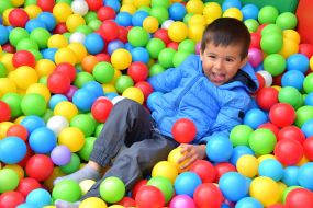 The boy is playing in the pool with balls