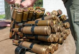 A serviceman inserts ammunition into a machine gun tape