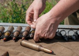 A serviceman inserts ammunition into a machine gun tape