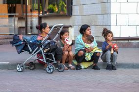 Women with children sit on the sidewalk