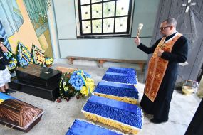 The priest sprinkles holy water on the coffin
