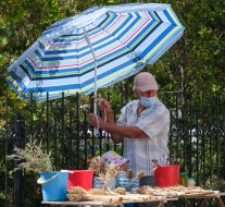 A man ties an umbrella to a fence