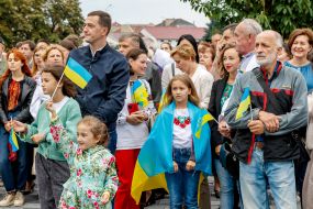 Люди держат флажки во время церемонии поднятия самого высокого на Закарпатье Флага Украины
