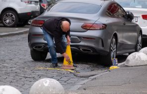 A man paints a road cone yellow