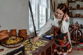 A girl in Hutsul national dress is frying potatoes on the stove in the museum of local lore