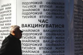 Men pass by posters calling for vaccinations