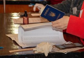 A member of the election commission holds a voter's passport at a polling station in Kharkiv