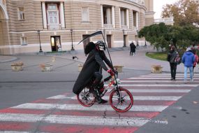 A man in a death suit on a bicycle