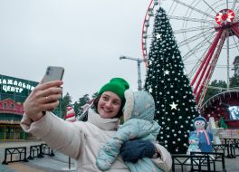 Woman with a child are photographed on the background of the Christmas tree