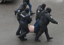 Сотрудники полиции несут задержанного нарушителя