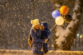 Woman with a boy in her arms carries balls in snowy weather