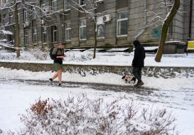 A young man in shorts walks in a snow-covered park