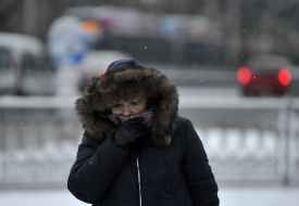 Женщина заслоняет лицо шарфом на улице в Киеве