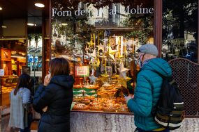 Tourists in protective masks view a window with pastries in Barcelona