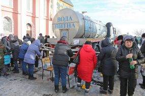 Believers collect drinking water from a barrel