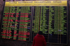 Passengers at the board with the schedule of trains