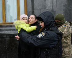 Представниця міжнародного громадського руху FEMEN з дитиною на руках та правоохоронці