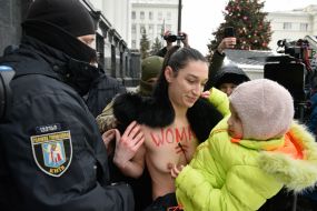 Представниця міжнародного громадського руху FEMEN з дитиною на руках та правоохоронець