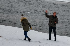 Young couple playing snowballs near the river Uzh