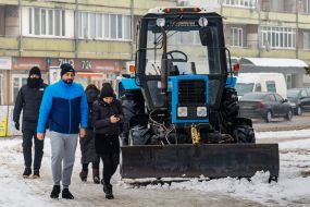 People pass by snow removal equipment