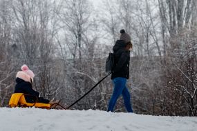 Женщина тянет санки по заснеженному парку