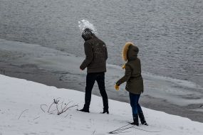 Молодая пара играет в снежки у реки Уж
