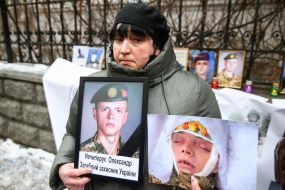 A woman holds photos of a dead soldier