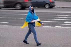 A guy with the flag of Ukraine carries pizza